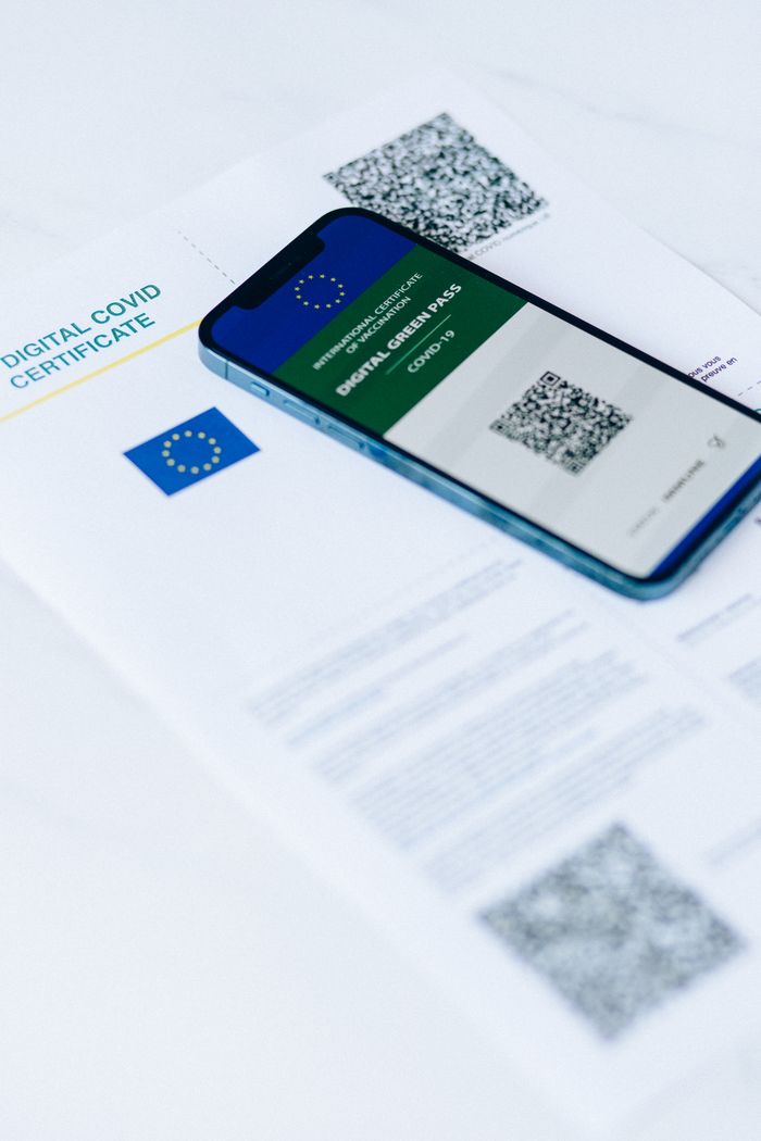 Smartphone showing digital COVID pass on document with QR codes.